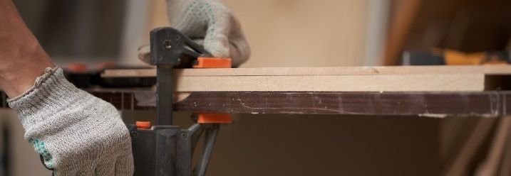Furnier wird mit einer Schraubzwinge und einem Stück Holz festgedrückt
